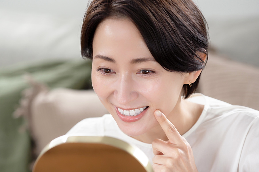 鏡で歯を見る女性